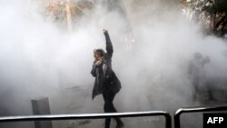 Иран. Тегеранда нааразылыкка чыккан аял көздөн жаш агызчу газ атылган учурда муштумун көрсөтүүдө. 30-декабрь, 2017-жыл.   