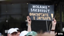 Протестиращ е вдигнал плакат с надпис "Искаме законност, олигарсите в затвора".