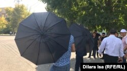 Неизвестные в Шымкенте с зонтами препятствуют репортеру Азаттыка вести съемку. 21 сентября 2019 года.