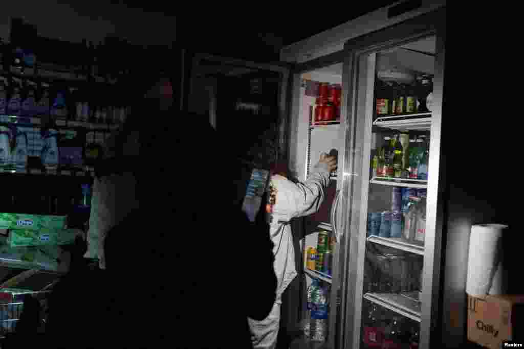 Люди используют свои телефоны и налобные фонарики, чтобы купить продукты в супермаркете во время отключения электричества в Барселоне, Испания, 28 апреля 2025 года. REUTERS/ Bruna Casas