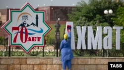 Уборщица на фоне городских украшений в честь 70-летия Ахмата Кадырова, архивное фото