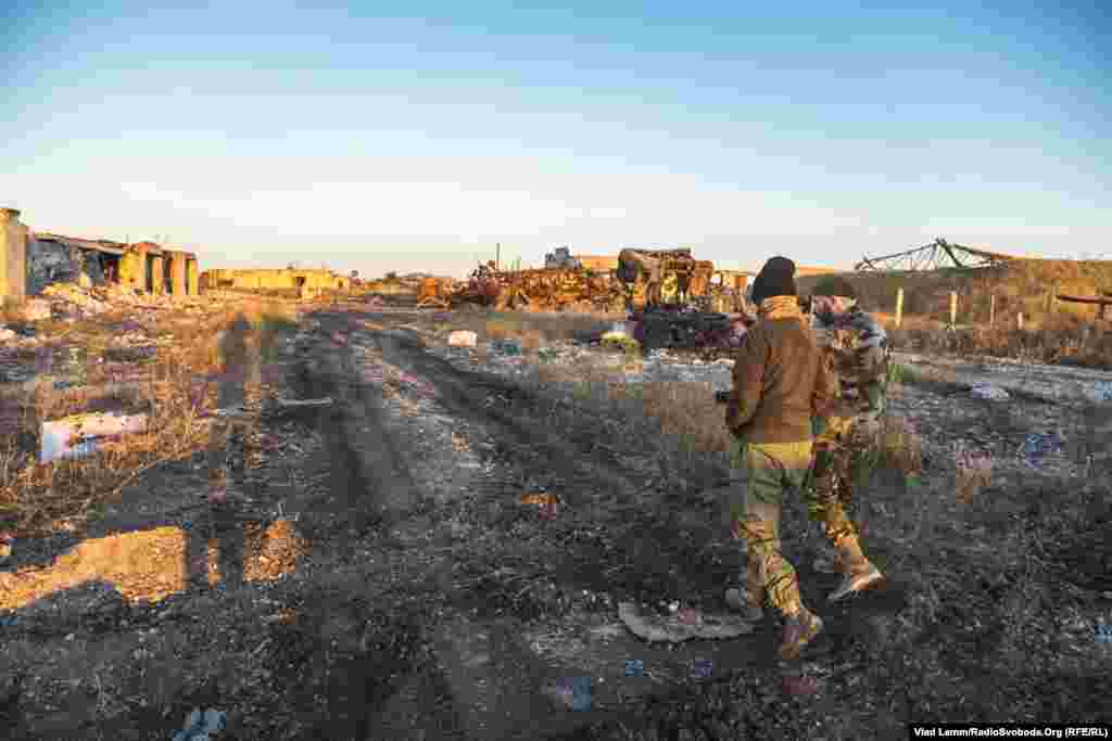 Волонтер Юрій йде біля зруйнованих складських приміщень разом із бійцем 93-ї бригади​