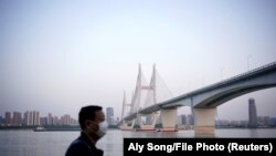 Чоловік, що носить маску для обличчя, биля річки Янцзи в Ухані після того, як було знято карантин в Ухані, столиці провінції Хубей, епіцентрі нової коронавірусної хвороби в Китаї.