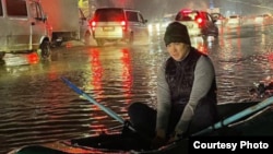 Болот Ибрагимов на надувной лодке в крупной луже на дороге в Бишкеке.