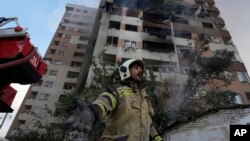 Израильдің Иранға әуе шабуылынан бүлінген көпқабатты тұрғын үйдің қасында тұрған өрт сөндіруші. Тегеран, 13 маусым, 2025 жыл.