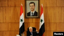 ولید المعلم، وزیر خارجه سوریه زیر عکسی از بشار اسد، رییس جمهوری این کشور.