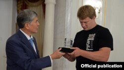 Президент Атамбаев жаҳон чемпиони Поветкинга Манас рамзи туширилган сувенирни топширмоқда.