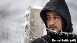 A migrant stands next to a fence during snowfall at the Lipa camp outside Bihac on January 8.