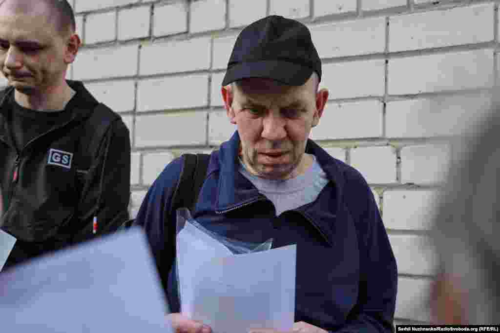 Український військовий, який повернувся з полону РФ, розглядає фото, які йому показують рідні військовополонених та зниклих безвісти