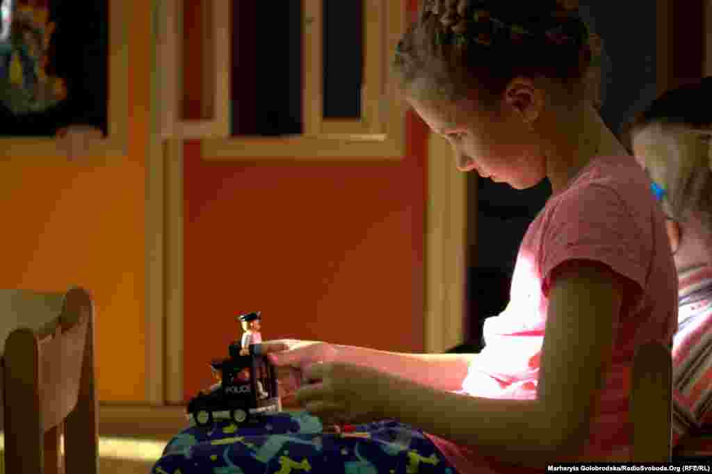 Валерія зі Львівщини зацікавлено роздивляється іграшкове авто поліції