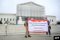 Протестиращи срещу политиката на Тръмп държат банер пред сградата на Върховния съд на САЩ, 27 юни 2025 г.