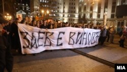 Opposition protesters in Skopje carry a banner that says the country's former prime minister is guilty of abuse of power.