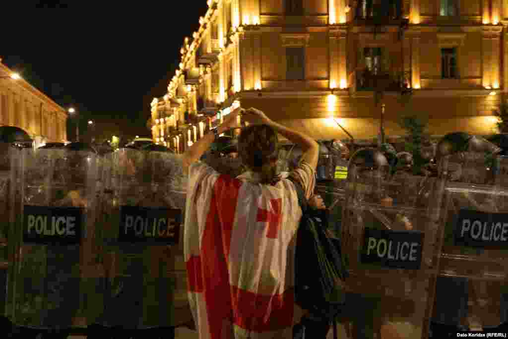 Дівчина, огорнувшись національним прапором, показує жест любові серед натовпу силовиків