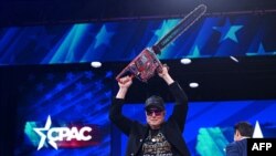 Илон Маск с бензопилой, символом сокращения госрасходов на мероприятии консерваторов в Мэриленде в феврале 2025 года