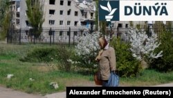 Bir aýal Russiýanyň Ukraina uran zarbalary netijesinde weýran bolan jaýyň öňünden ýöräp barýar (arhiw suraty)