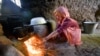 A girl lights a cooking fire in Tajikistan's Khatlon region.
