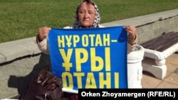 Зағип әйел Қазына Махмедова "Нұр Отан" партиясына наразылық жазылған плакат ұстап  Астананың орталығындағы алаңда отыр. 12 қыркүйек 2013 жыл.