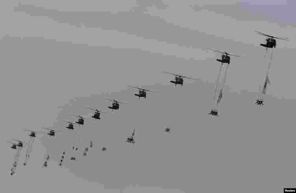 Военнослужащие сил специального назначения, спущенные на тросах с вертолетов во время авиашоу на военном аэродроме к югу от Сеула