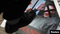 Сүрөттө: түштүк кореялык демонстрант Түндүк Кореянын жол башчысынын сүрөтүн тепсеп жатат, 25-май, 2010-жыл.