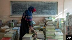 Кабул мектебіндегі ауған мұғалімі кітаптарды топтастырып жатыр. 2022 жылғы желтоқсан.