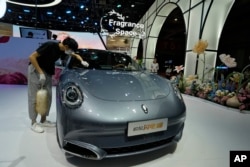 Рабочий протирает Ora, электромобиль китайского бренда, во время Шанхайского автосалона 2023 года в Национальном выставочном и конференц-центре в Шанхае, Китай, 18 апреля 2023 года