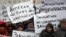 People hold placards as they pay tribute to the 12 people killed by two gunmen at the French weekly newspaper Charlie Hebdo's editorial office, outside French Embassy in Moscow on January 9.