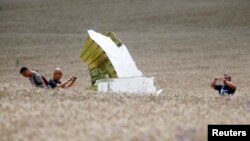 گروه اعزامی از مالزی در محل در حال عکس‌برداری از باقی‌مانده هواپیمای سرنگون شده