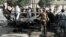 Afghan security forces inspect the wreckage of a passenger van after a bombing in Kabul on June 12.
