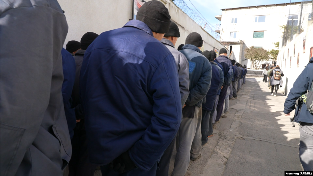 Російські військовополонені вишикувалися в колону, щоб організовано зайти до їдальні. За Третьою Женевською конвенцією, не показуємо їхні обличчя. Табір дозволяють відвідати журналістам. У групі, в якій побували кореспонденти Крим. Реалії (проєкт Радіо Свобода) було також багато представників іноземних ЗМІ