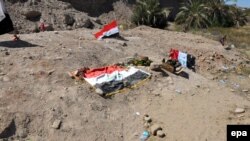 پرچم‌های عراق بر خاک، جایی که گمان می‌رود گور دسته‌جمعی قربانیان کشتار اسپایکر باشد