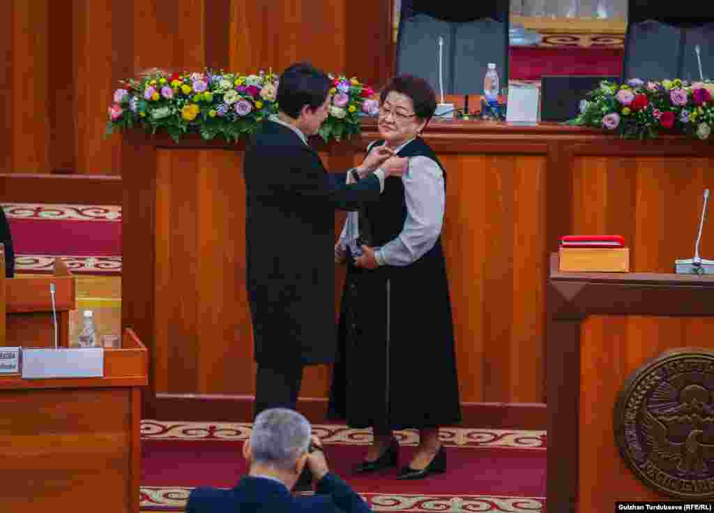 БШКнын төрайымы Нуржан Шайлдабекова&nbsp;Шарапаткан Мажитовага депутаттык&nbsp;төш белгини тапшырып жатат.​