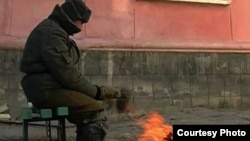 Житель города греется на улице у костра возле дома в Приозерске. Январь 2011 года.  