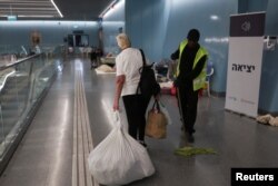 Израиль мен Иранның өзара атысты доғару келісімі күшіне енгеннен кейін, осыған дейін өзі паналаған жер астындағы теміржол станциясынан жүгін көтеріп шығып келе жатқан адам. Рамат-Ган, Израиль, 24 маусым, 2025 жыл.