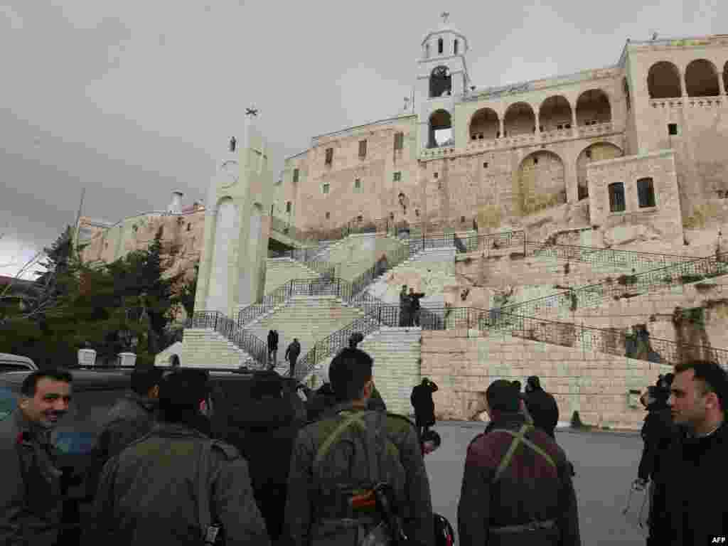 Военные сопровождают журналистов, которые осматривают монастырь, пострадавший во время военной операции.