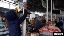 A supporter of the Islamic Renaissance Party of Tajikistan (IRPT) pastes a campaign poster at a market in the capital, Dushanbe, in 2015, the year it was banned in the country and labeled a terrorist group.
