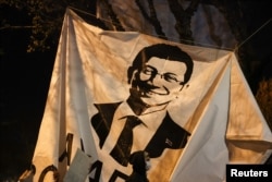 Человек проходит мимо баннера с изображением Экрема Имамоглу во время акции протеста против его задержания в Стамбуле 20 марта