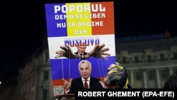 Плакат на акції протесту, на якому зображений керівник Росії Володимир Путін і Келін Джорджеску, який пройшов до другого туру на виборах президента Румунії. Конституційний суд скасував ці результати у звʼязку з ймовірним іноземним втручанням. Бухарест, листопад 2024 року
