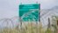 Georgia -- A warning sign is pictured behind a wire barricade erected by Russian and South Ossetian troops along Georgia's de-facto border with its breakaway region of South Ossetia in the village of Khurvaleti, July 14, 2015