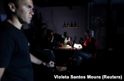 Люди в кафе изучают меню под светом фонарика мобильного телефона