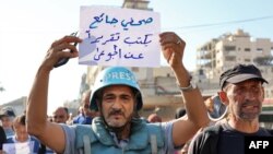 یک خبرنگار در غزه پلاکاردی را در دست دارد که روی آن نوشته شده «خبرنگار گرسنه گزارشی دربارۀ گرسنگان می‌نویسد»