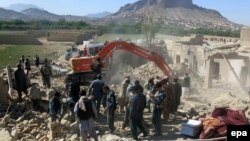 Afghan security forces inspect the site of a blast at a police arms depot in Kandahar on April 21.