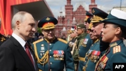 На фотографии, распространенной российским государственным агентством Sputnik, президент России Владимир Путин приветствует военачальников после военного парада Победы на Красной площади в Москве 9 мая