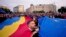 Учасники акції тримають великі прапори Румунії та Євроcоюзу під час мітингу напередодні переголосування президентських виборів у Бухаресті, Румунія, 9 травня 2025 року