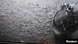 Көлүк-робот "Curiosity" Марстын бетине конор замат жөнөткөн фотосүрөттөн аппараттын бир дөңгөлөгү  көрүнүп турат. 6-август 2012