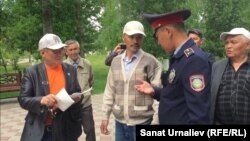 Жители Уральска во время несанкционированной акции на аллее памяти жертв политических репрессий: слева направо Максат Айсаутов, Махсот Кубеев, Альбек Ергазиев, сотрудник полиции и Искак Азбергенев. Уральск, 31 мая 2018 года. 