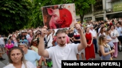 Мъж държи плакат с колаж на прасе и тиква, София, 22 юли 2025 г.