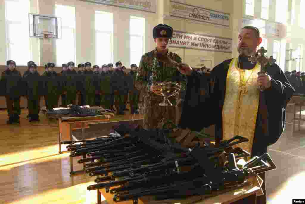 Православний священик благословляє автомати під час церемонії отримання зброї новобранцями на військовій базі МВС Білорусі в Мінську, 23 січня 2013 року