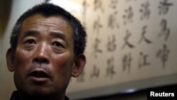 Китаец на фоне стенда на китайском языке. Иллюстративное фото.  