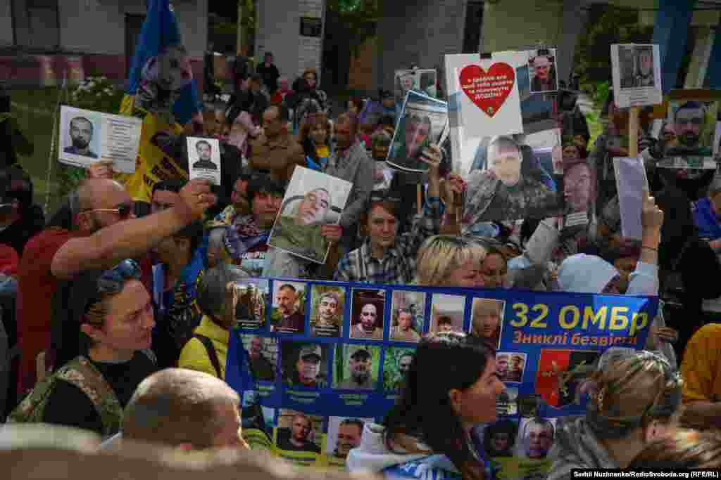 Люди показують портрети своїх близьких, щоб дізнатися у бійців, які повернулися з російського полону, інформацію про рідних