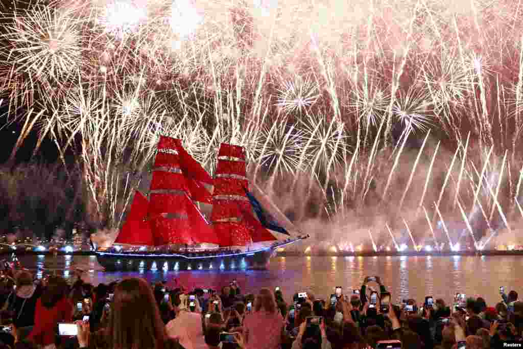 Санкт-Петербургда мектеп бүтүрүүчүлөрдүн урматына өткөрүлгөн майрам. Жээктеги адамдар Нева дарыясында сүзүп бараткан кемени карап турушкан кези. 